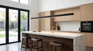 An ultra-thin black and brass linear LED suspension fixture hanging horizontally over a modern marble kitchen island.